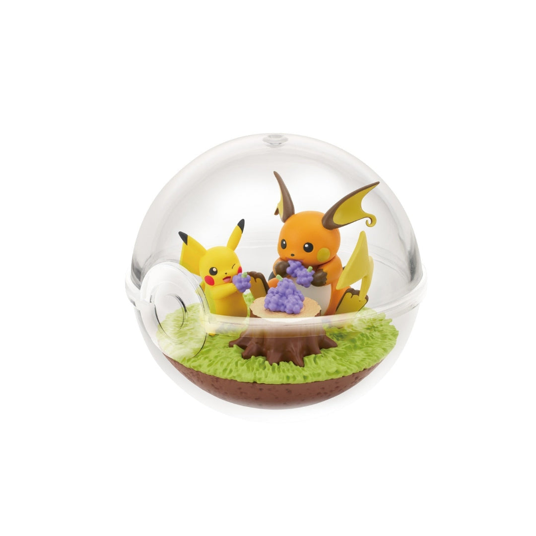 A small terrarium-style figure featuring Pikachu and Raichu from Pokémon sitting around a tree stump, holding bunches of purple berries. The scene is enclosed in a clear Poké Ball-shaped case with green grass-like terrain.