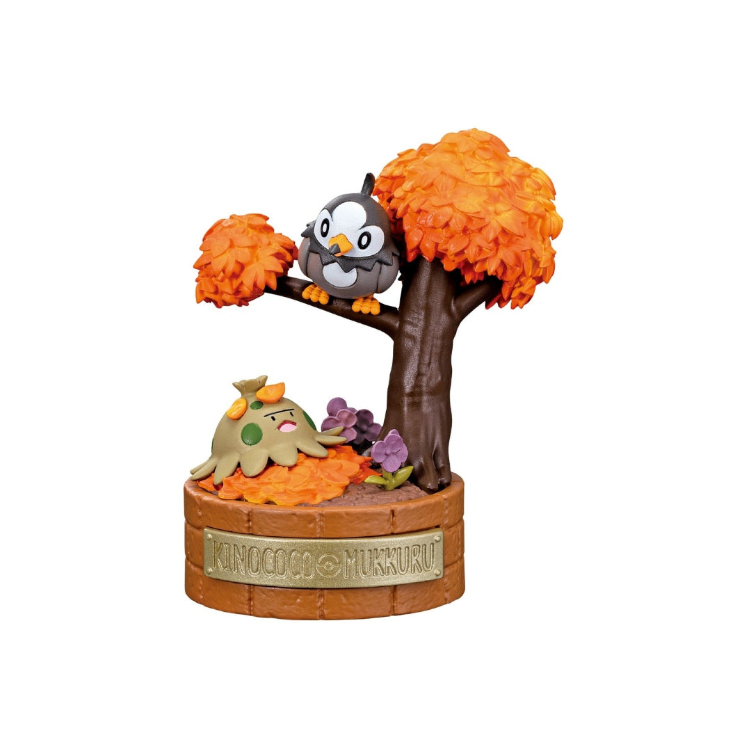A small Pokémon figure featuring Shroomish lying among orange autumn leaves and Starly perched on a tree branch above. The scene includes purple flowers and a large brown tree with orange foliage, all set on a round base labeled “KINOCOCO & MUKKURU.”