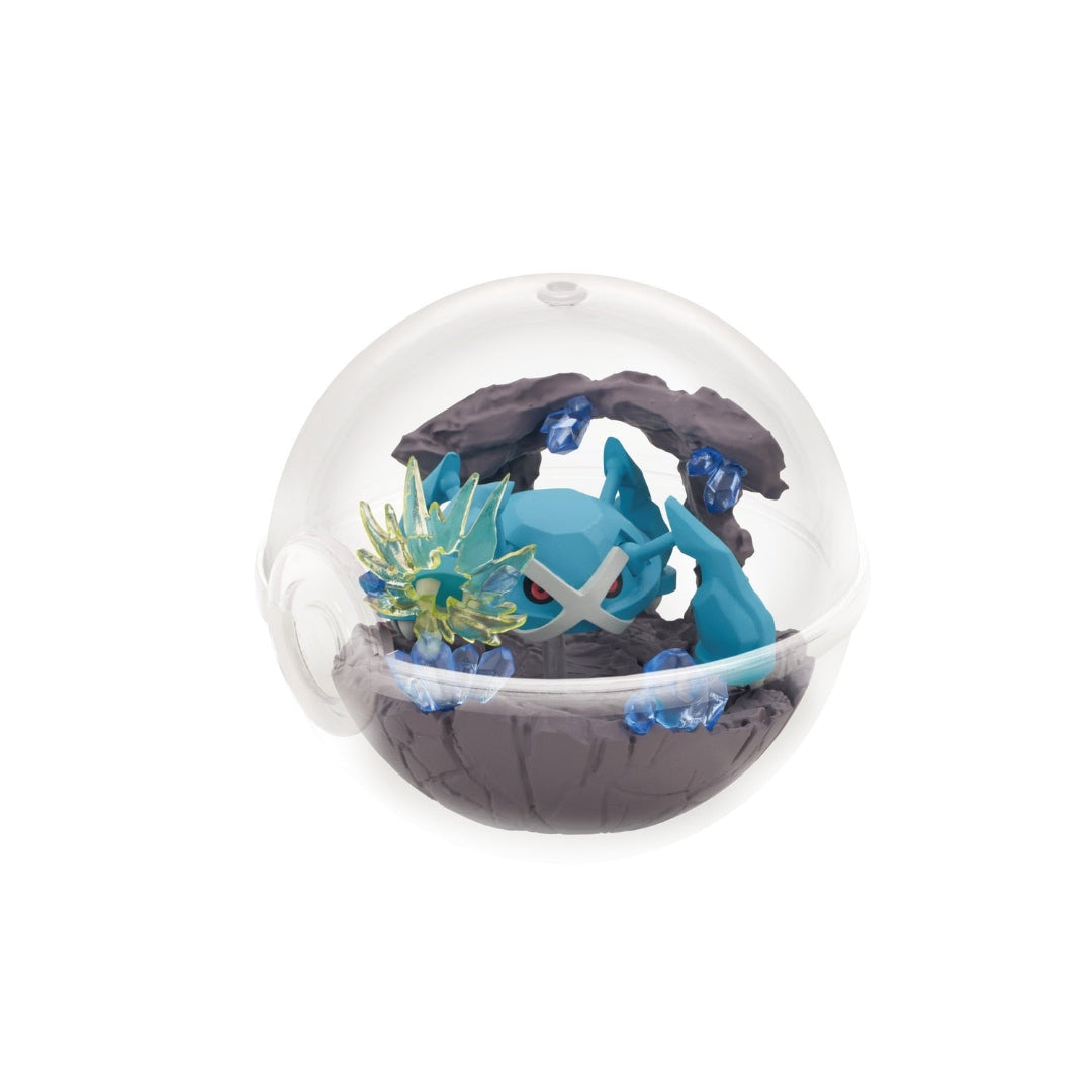 A terrarium-style figure of Metagross from Pokémon, displayed inside a clear Poké Ball-shaped case. Metagross is crouched beneath a rocky arch surrounded by jagged crystals and translucent blue shards, creating a cave-like setting.