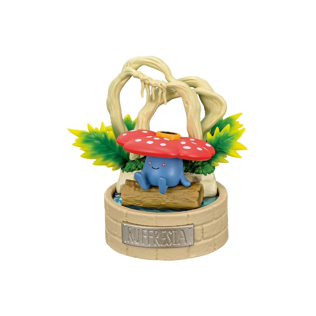 A decorative Pokémon figure of Vileplume sitting on a log in front of a twisted tree and lush greenery. The display features a circular base labeled "Ruffresia" and includes a small water element beneath the log.