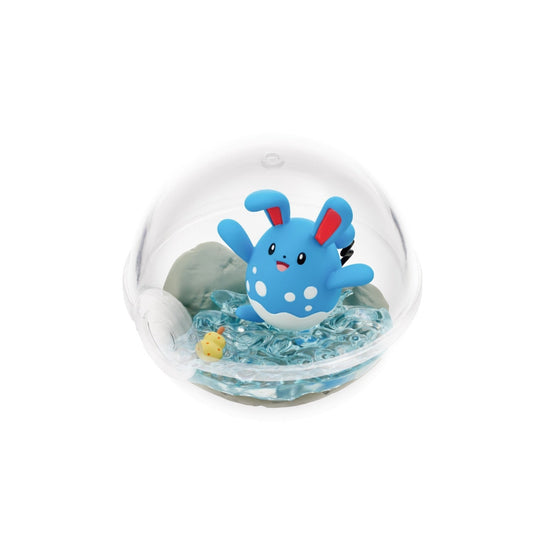 A terrarium-style figure of Azumarill from Pokémon inside a clear Poké Ball-shaped case. Azumarill is joyfully splashing in clear blue water with a small yellow berry nearby, set against a rocky background.